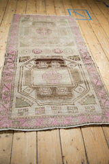 Full length angled view of a distressed Kurd runner with fuchsia and brown geometric medallions.