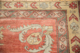 Distressed Kurdish carpet corner, showing low pile, faded coral field, and scrolling tribal motifs.