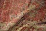 Distressed texture with muted coral, beige geometric patterns on a folded vintage Kurdish rug.