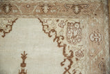 Corner detail of a vintage Oushak rug with serrated leaf and palmette border motifs.