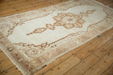 Angled perspective of a vintage Oushak runner with a brown starburst medallion on an open ivory field.
