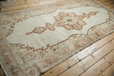 Angled view of a distressed Oushak runner, highlighting its neutral medallion and low-pile texture.