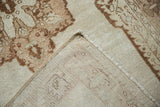 Folded corner of a vintage Oushak rug showing its hand-knotted foundation and side cord.