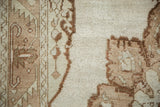 Visible knot heads and low pile in coffee brown and ivory on a distressed Oushak rug.