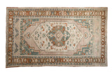 Distressed vintage Taspinar carpet featuring a central medallion in soft peach, teal, and cream.