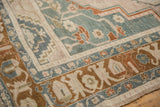 Section of a distressed Taspinar rug showing geometric motifs in sage, rust, and cream.