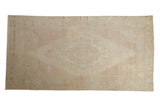 Vintage distressed Oushak rug runner with a central cameo medallion in soft sand, pink, and seafoam green.