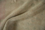 Close view of mostly even wear on the sandy, hand-knotted pile of a distressed Oushak rug.