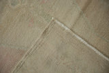 Folded corner of a distressed Oushak rug showing the hand-knotted foundation and low-pile texture.