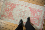 Vintage Oushak rug runner in pale raspberry and seafoam green shown to scale from an overhead view.