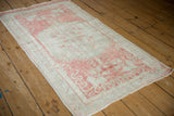 Angled view of a distressed Oushak runner, showing its soft wear and faded raspberry floral pattern.