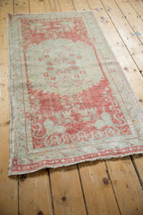 Angled view of the distressed Oushak runner showing its soft raspberry and seafoam green tones.