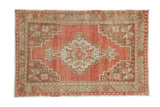 Distressed Oushak rug with a geometric stepped medallion and starburst florals in brick red and beige.