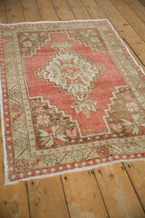 High-angle view of a distressed Oushak rug showcasing its brick red field and geometric medallion.