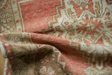 Folded corner of a distressed Oushak rug showing its low pile and even wear.