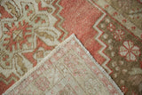A folded corner reveals the hand-knotted construction of a vintage Oushak rug.