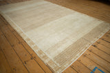 Angled perspective of a distressed Kars carpet showing heavy abrashes across the beige geometric field.
