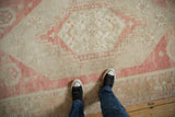 Overhead view of a distressed Oushak rug's low pile, revealing its rose and ivory stepped medallion.