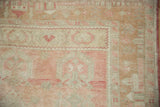 Detail of the pictorial village scene border in soft rose, sand, and ivory on a distressed Oushak rug.
