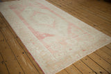 Angled perspective of a distressed Oushak rug with a stepped medallion and faded rose palette.