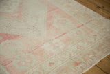 The heavy abrashes and low, distressed pile of a vintage Oushak rug in soft rose and ivory.