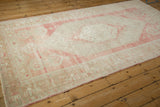 Angled view of a distressed Oushak rug, showing the heavy abrashes in rose and ivory tones.