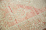 Close-up showing the distressed texture and heavy abrash in rose and sand colors.