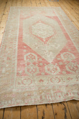 Perspective view of the distressed Oushak rug highlighting its soft rose and sand color palette.