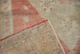 Corner view of a distressed Oushak rug revealing its hand-knotted foundation and secured selvage.