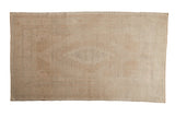 Vintage distressed Oushak rug with a faded geometric medallion in neutral tones of sand, ivory, and dusty rose.