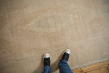 Evenly worn low-pile texture of a distressed vintage Oushak rug in soft sand and cream tones.