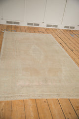 Low angle of a vintage Oushak rug highlighting its even wear and soft sand-colored pile.