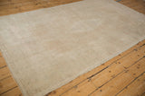The even, low-pile texture of a distressed Turkish Oushak rug in soft neutral tones.