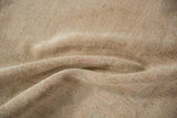 Reverse view of a distressed Oushak rug showing its hand-knotted foundation in sandy tones.