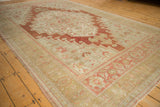 Distressed vintage Turkish Oushak rug corner, showing worn terracotta borders and faded floral motifs.
