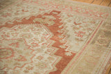 Distressed Oushak rug with faded terracotta geometric patterns on a soft beige field.