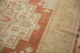 Distressed vintage Oushak carpet showing worn peach and neutral geometric patterns.