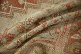 Distressed pile texture on a folded vintage Oushak carpet with muted earthy tones.
