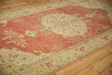 Distressed faded red pile and beige arabesque vines, with visible knot heads and mostly even wear.