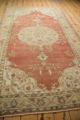 Distressed Anatolian rug's faded red field, beige border, and original side selvage.