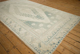Distressed texture of a vintage Oushak rug corner, with soft blue and cream border.