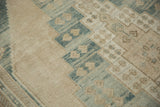 Distressed vintage Oushak rug with muted blue-green and beige geometric pattern detail.