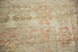 Distressed texture of a vintage Turkish rug with visible knot heads and pale blush and ivory motifs.
