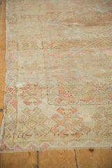 Distressed texture of a vintage rug showing low pile, knot heads, and pale blush accents.