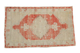 Vintage distressed Oushak rug with a large, geometric raspberry red medallion on an antique ivory field.