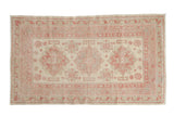 Vintage distressed Anatolian rug with a triple starburst medallion in pale raspberry red and silver on an ivory field.