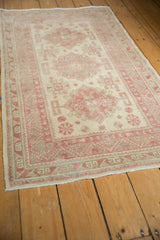 Angled view of a vintage Anatolian rug's triple starburst medallions in blush and silver.