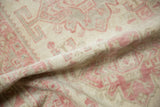 Supple hand-knotted texture and distressed low pile in pale raspberry and ivory.