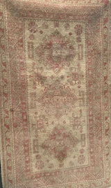 Close-up of distressed Anatolian rug pile, faded raspberry and ivory, showing noted stain.