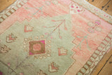 Distressed Oushak rug detail featuring blush pink, sage abrash, and hook latch motif.